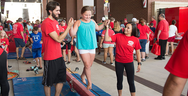 Gamma Phi members helping a girl to walk on a tight-wire.